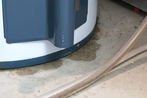 Blue and white water heater leaking on a residential basement floor in the Metro East.