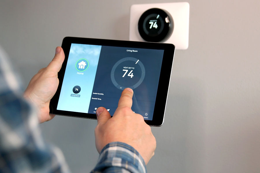 A homeowner using a smart device to change the temperature of their home using a new thermostat in the Metro East.