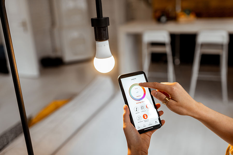 A homeowner in the Metro East using a smartphone to change the lights in her living room using smart energy-efficient bulbs.