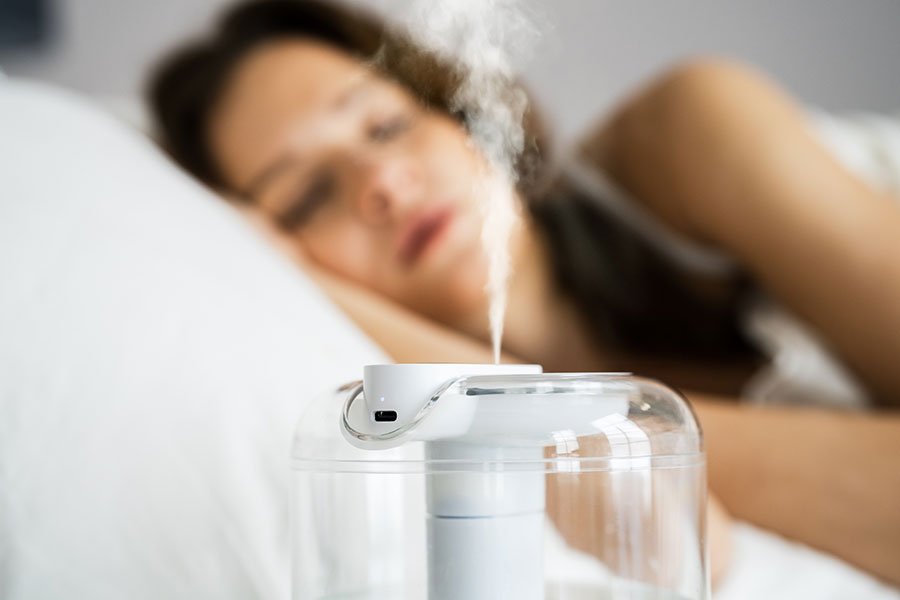 A sick woman lying in bed in the Metro-East and using a humidifier to regain health and break up congestion.