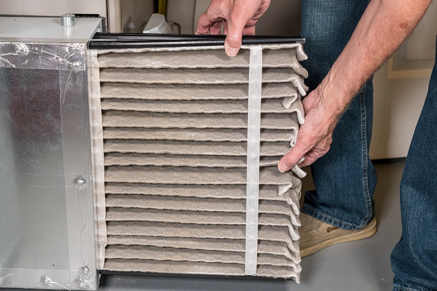 Technician conducting a furnace maintenance service by changing out a dirty air filter while winterizing a home in the Metro East Area.
