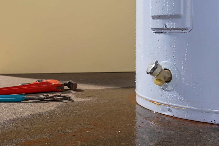 Up close picture of water on the ground near a leaking water heater with tools nearby in the home of a Metro East Area resident.